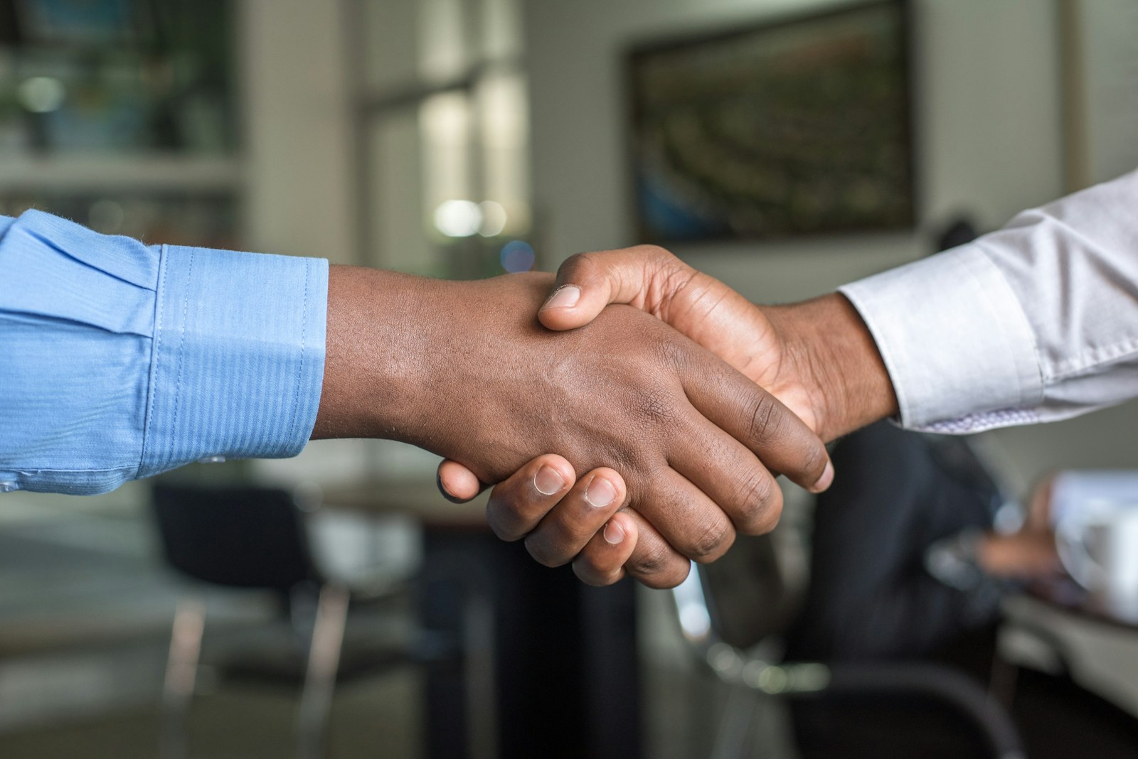 An advisor and client shaking hands across a desk